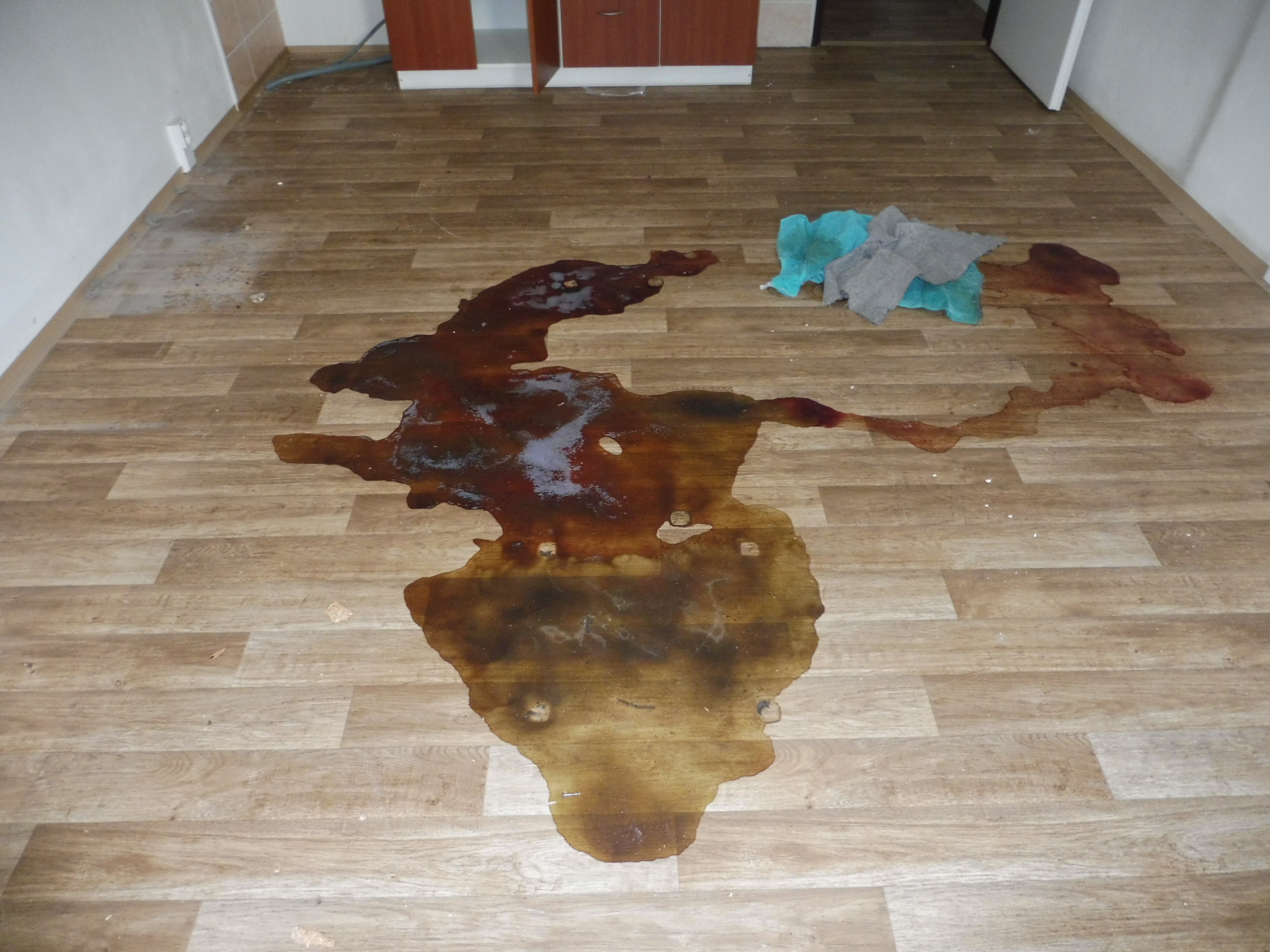 Prázdná místnost s podlahou znečištěnou biologickými tekutinami před odbornou dezinfekcí po úmrtí.